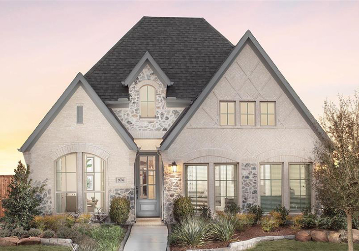This Perry Homes’ Design 1950W features light natural brick arranged in a herringbone pattern and a natural stone façade